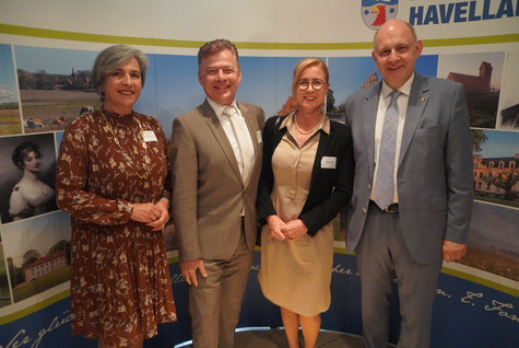 Der Landrat und die Kreistagsvorsitzende begrüßen die Gäste des Sommerempfangs vor einer Werbewand zum Landkreis Havelland - Klick öffnet Bildbetrachter