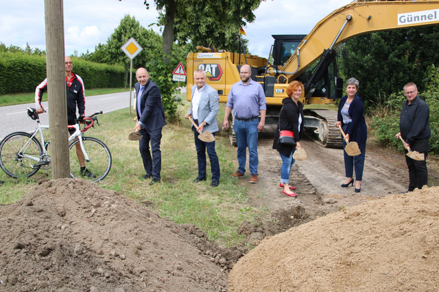 Mehrere Menschen stehen in einer Reihe und führen einen Spatenstich aus.