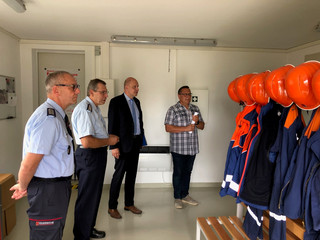 Vier Männer stehen in einem Umkleideraum der Feuerwehr.