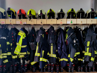 Foto einer Garderobe der Feuerwehr mit Jacken und Helmen - Klick öffnet Bildbetrachter