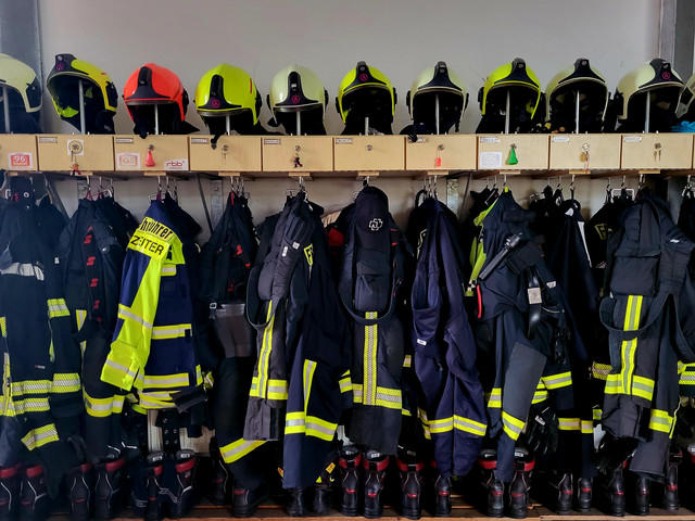 Foto einer Garderobe der Feuerwehr mit Jacken und Helmen - Klick öffnet Bildbetrachter