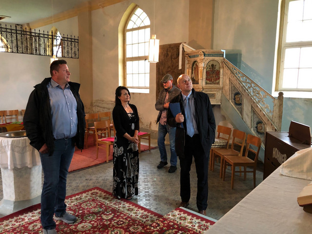 Vier Personen stehen in einer Kirche und schauen sich um.