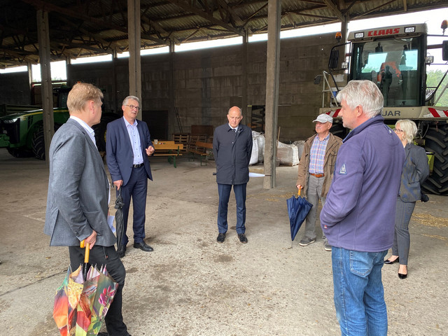 Eine Gruppe von Menschen steht im Kreis in einer Scheune.