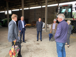 Eine Gruppe von Menschen steht im Kreis in einer Scheune.