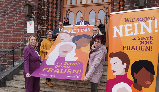 Klick öffnet Text; eine Gruppe von Menschen halten eine Fahne