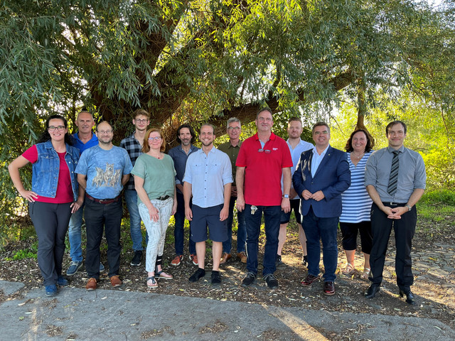Eine Gruppe von Menschen steht unter einem Baum - Klick öffnet Bildbetrachter