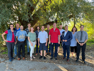 Eine Gruppe von Menschen steht unter einem Baum - Klick öffnet Bildbetrachter