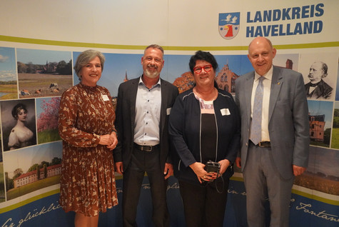 Der Landrat und die Kreistagsvorsitzende begrüßen die Gäste des Sommerempfangs vor einer Werbewand zum Landkreis Havelland - Klick öffnet Bildbetrachter