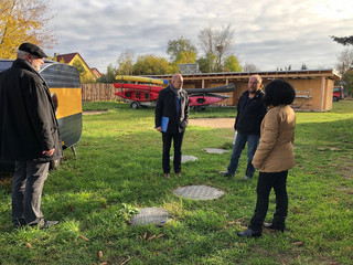 Vier Personen stehen in einigem Abstand auf einem Hof und unterhalten sich.