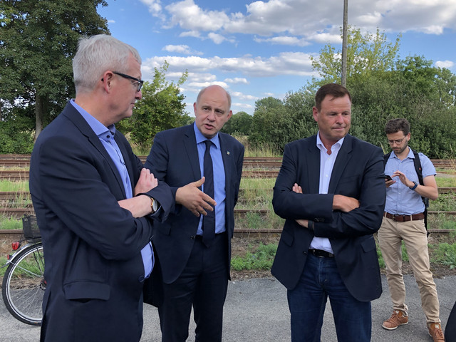 Drei Männer stehen im Halbkreis und unterhalten sich.