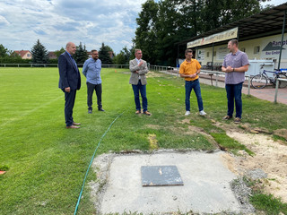 Fünf Männer stehen auf dem Mögeliner Sportplatz und unterhalten sich.