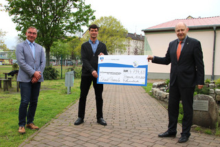 Bürgermeister Tebling, Schulleiter Martin (mit Spendenscheck) und Landrat Lewandowski stehen auf dem Außengelände der Oberschule Premnitz.