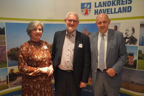 Der Landrat und die Kreistagsvorsitzende begrüßen die Gäste des Sommerempfangs vor einer Werbewand zum Landkreis Havelland - Klick öffnet Bildbetrachter