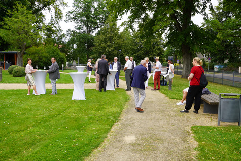 Gäste der Veranstaltung stehen verteilt auf einer Grünfläche vor dem Schloss Ribbeck - Klick öffnet Bildbetrachter