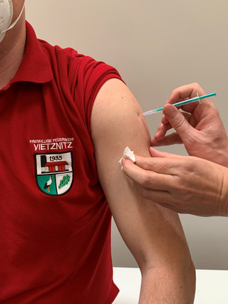 Ein Feuerwehrmann bekommt eine Impfung in den Oberarm gespritzt.