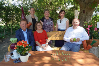 Gruppenbild in einer Sitzgruppe, drei Personen sitzen auf einer Bank und drei stehen dahinter - Klick öffnet Bildbetrachter