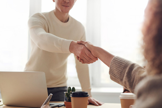 Zwei Personen begrüßen sich mit Handschlag