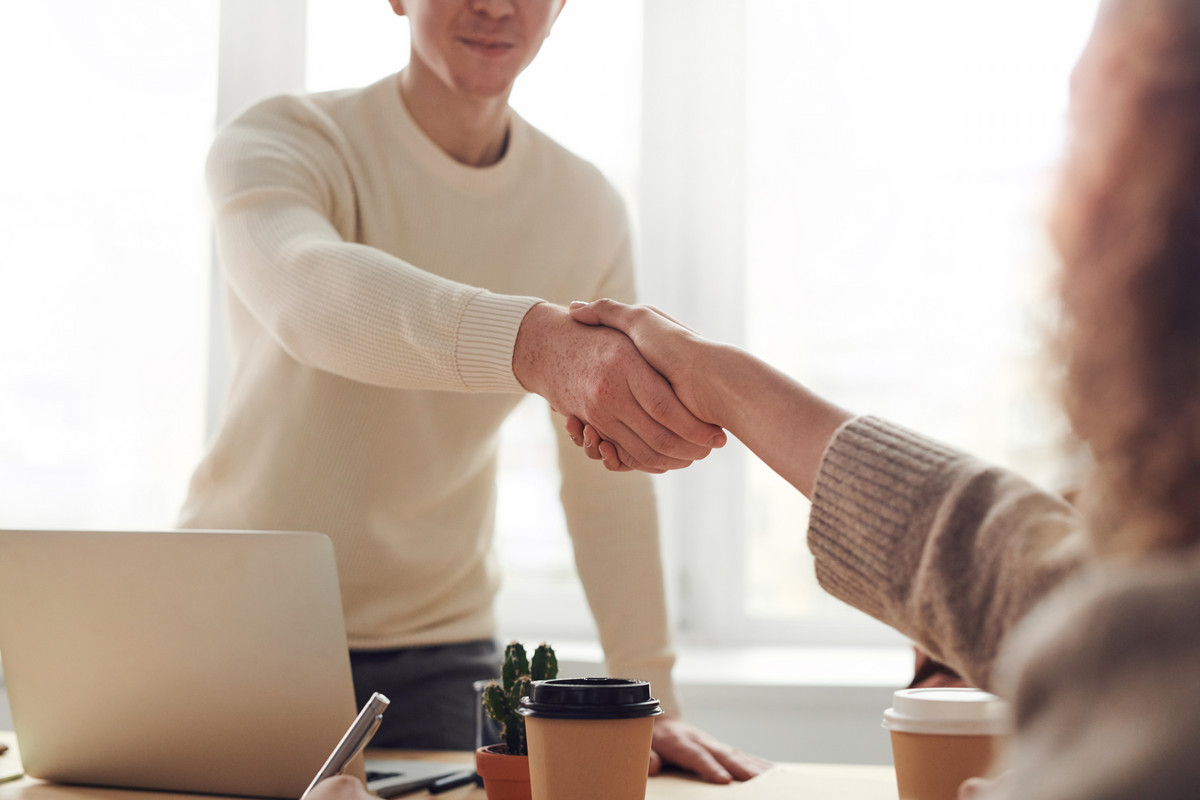 Zwei Personen begrüßen sich mit Handschlag