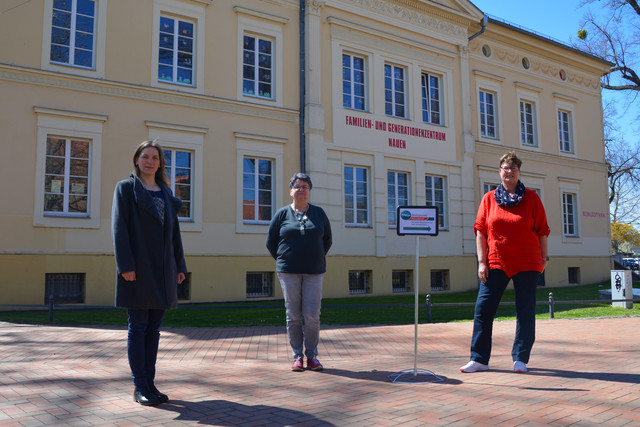 Drei Frauen stehen auf einem Platz, im Hintergrund ist das FGZ Nauen zu sehen.