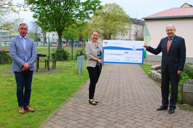 Bürgermeister Tebling, Schulleiterin Petzold (mit Spendenscheck) und Landrat Lewandowski stehen auf dem Außengelände der Oberschule Premnitz.