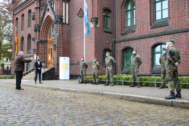 Bundeswehrsoldaten stehen aufgereiht vor dem Kreishaus in Rathenow. Dennis Granzow steht vor ihnen und spricht zu ihnen.