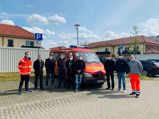 Einige Feuerwehrleute stehen auf einem Parkplatz vor einem Feuerwehrfahrzeug.