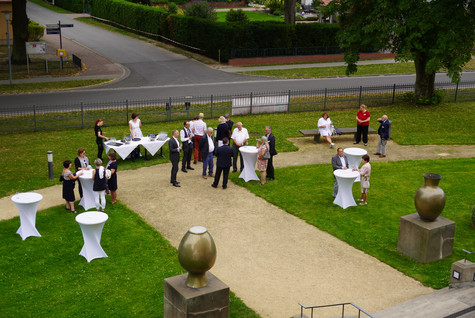 Gäste der Veranstaltung stehen verteilt auf einer Grünfläche vor dem Schloss Ribbeck - Klick öffnet Bildbetrachter