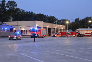 Ein Konvoi von Feuerwehrfahrzeugen fährt hintereinander mit eingeschaltetem Blaulicht.