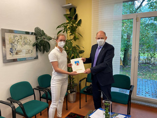 Denise Meseck und Landrat Lewandowski schauen in die Kamera. Zwischen sich halten sie den Zuwendungsbescheid.