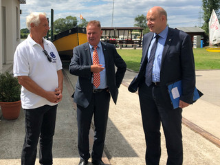 Drei Männer stehen auf dem Vereinsgelände und unterhalten sich.