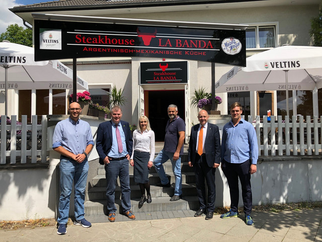 Sechs Personen stehen auf einer Treppe vor einem Restaurant.