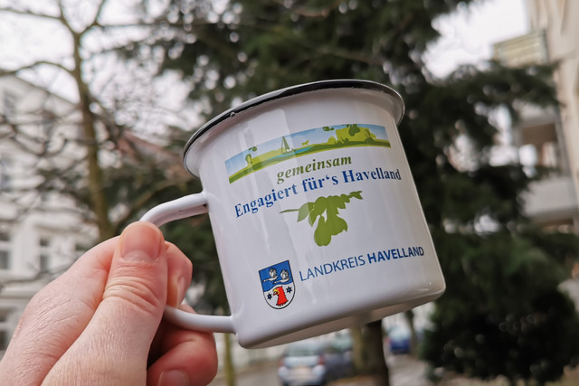 Eine Emailletasse mit dem Aufdruck "Gemeinsam engagiert fürs Havelland"