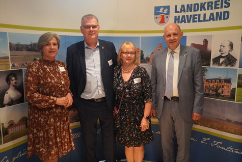 Der Landrat und die Kreistagsvorsitzende begrüßen die Gäste des Sommerempfangs vor einer Werbewand zum Landkreis Havelland - Klick öffnet Bildbetrachter