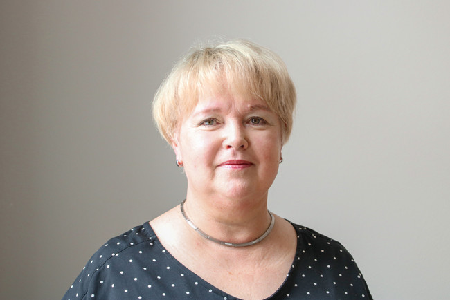 Christina Zubrytzki steht vor einer grauen Wand.