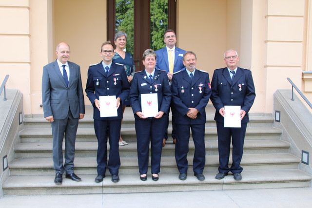 Die ausgezeichneten Feuerwehrleute stehen mit dem Landrat und zwei weiteren Personen auf einer Treppe.