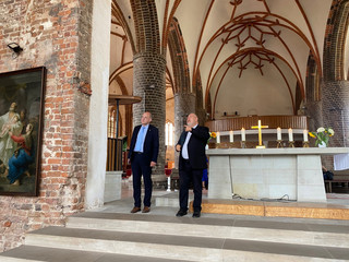 Zwei Männer stehen in der Kirche und schauen sich um.