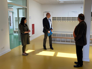 Drei Personen stehen in einem Schulflur und schauen sich um.