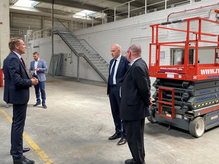 Drei Herren unterhalten sich in einer Lagerhalle.
