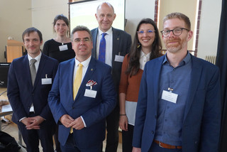 Sechs Personen stehen in einer Gruppe und schauen in die Kamera - Klick öffnet Bildbetrachter