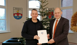 Klick öffnet Text; zwei Männer halten eine Blatt Papier