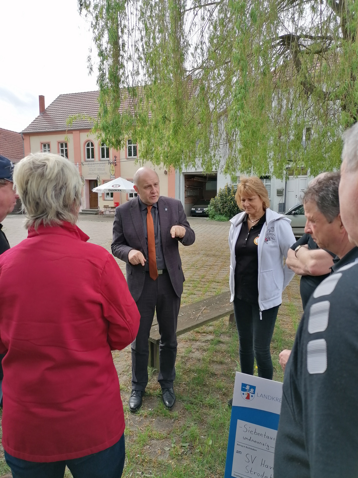 Klick öffnet Bildbetrachter; Gruppe von Menschen innerhalb eines Gebäudeensembles