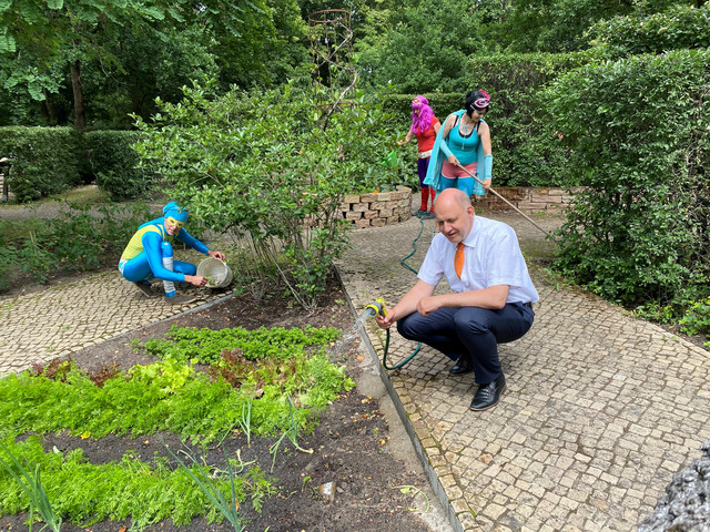 Landrat Roger Lewandowski gießt Blumen im Stinknormalen Stadtgarten von Rathenow.