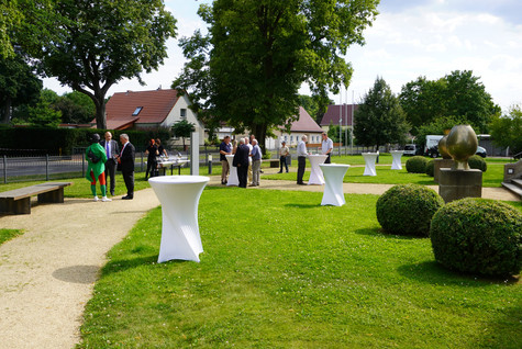 Gäste der Veranstaltung stehen verteilt auf einer Grünfläche vor dem Schloss Ribbeck - Klick öffnet Bildbetrachter