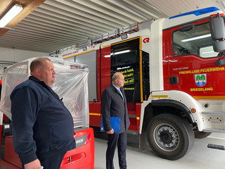 Zwei Männer stehen neben einem Feuerwehrauto.