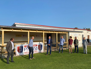 Sieben Männer stehen vor dem Vereinsgebäude.