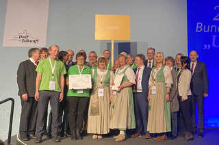 Menschen aus Garlitz stehen auf einer Bühne und zeigen ihre Auszeichnung.