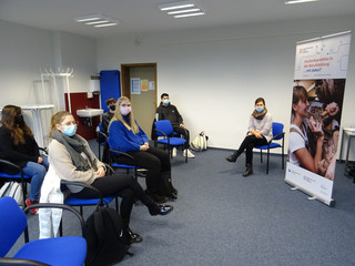 Eine Gruppe von Schülern sintzt mit der Referentin in einem Klassenraum.