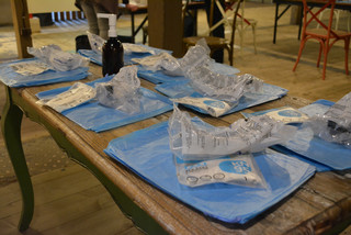 Auf einem Tisch liegen Mund-Nasen-Bedekcungen und Schutzanzüge.