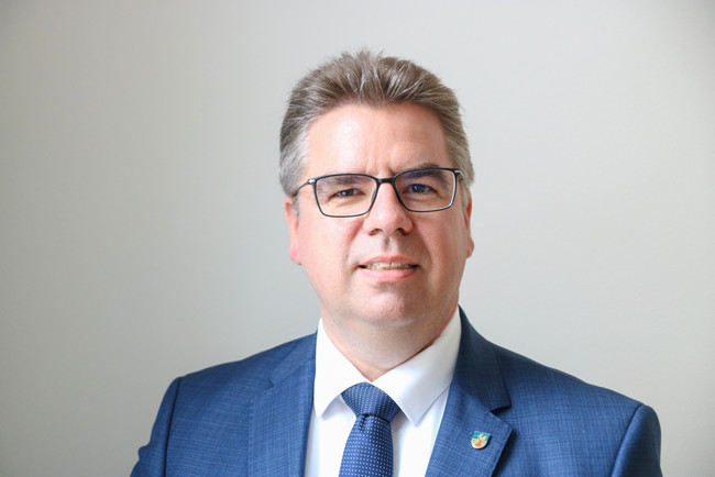 Michael Koch steht vor einer grauen Wand
