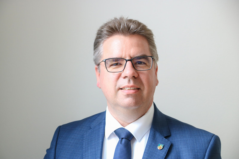 Michael Koch steht vor einer grauen Wand